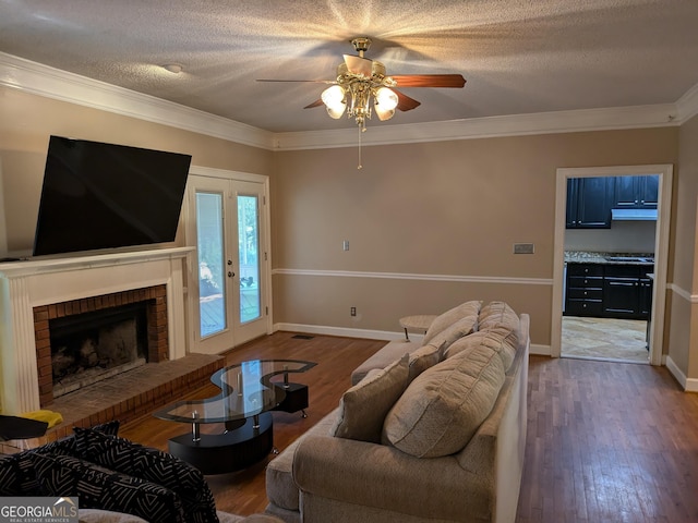 living room with crown molding, wood-type flooring, a textured ceiling, ceiling fan, and a fireplace