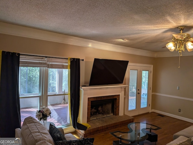 unfurnished living room featuring crown molding, wood-type flooring, a textured ceiling, ceiling fan, and a fireplace