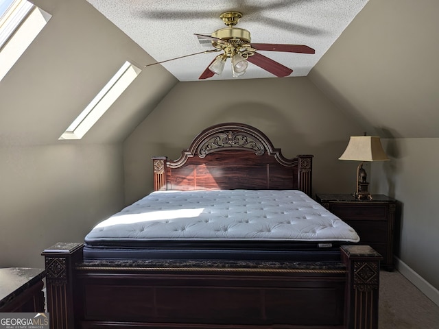 bedroom with lofted ceiling with skylight, carpet flooring, and ceiling fan