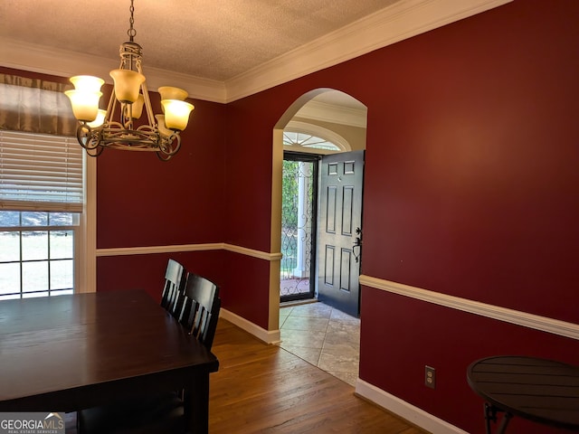 dining space featuring crown molding, hardwood / wood-style floors, a textured ceiling, and an inviting chandelier