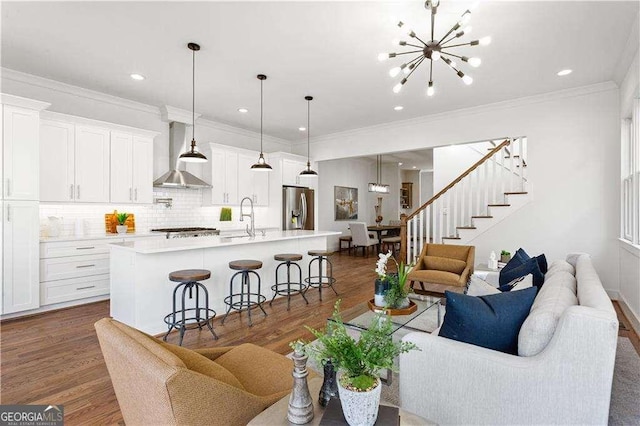 living room with crown molding, an inviting chandelier, dark hardwood / wood-style flooring, and sink