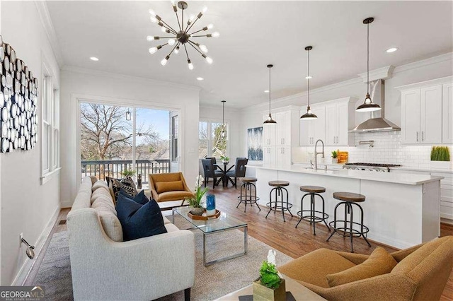 living room featuring ornamental molding, sink, a chandelier, and hardwood / wood-style floors