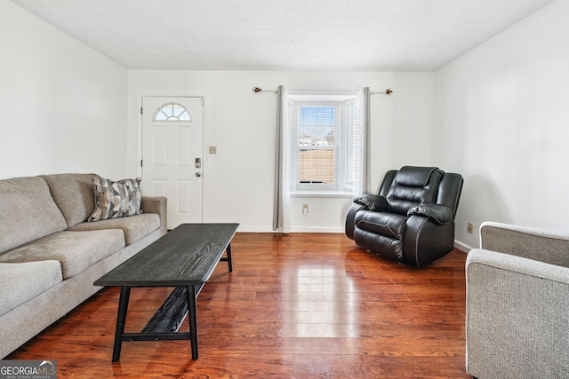 living room featuring a textured ceiling, baseboards, and dark wood-style flooring