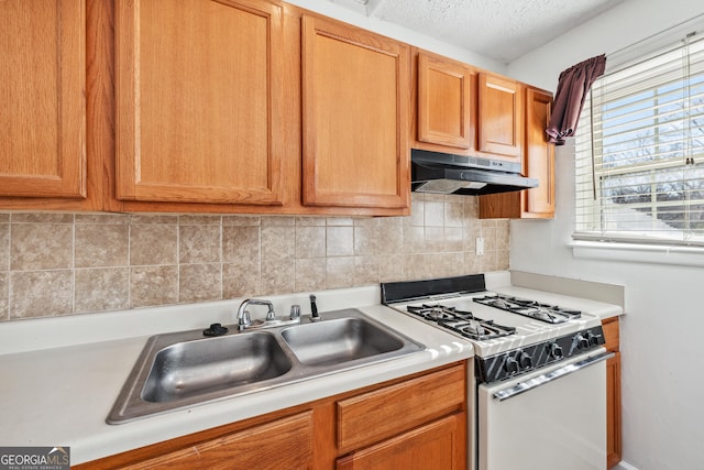 1625 Conley Rd Unit 270, Conley, GA 30288 - kitchen featuring white gas stove, under cabinet range hood, a sink, light countertops, and tasteful backsplash