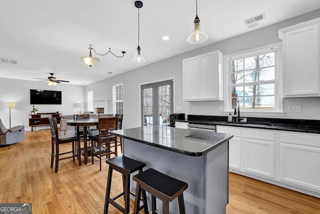 kitchen with a breakfast bar, decorative light fixtures, white cabinets, a center island, and french doors