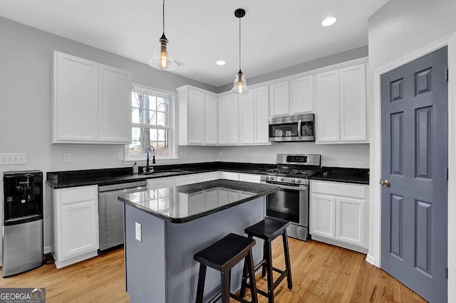 kitchen featuring sink, white cabinetry, a center island, light hardwood / wood-style flooring, and appliances with stainless steel finishes