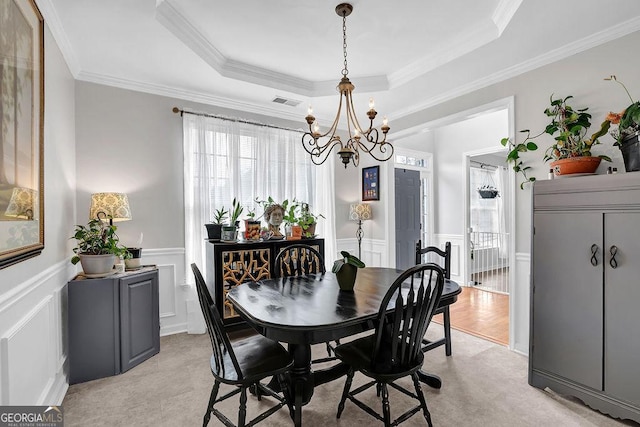 dining room with crown molding, a tray ceiling, and a notable chandelier