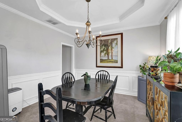 dining area with an inviting chandelier, ornamental molding, and a tray ceiling