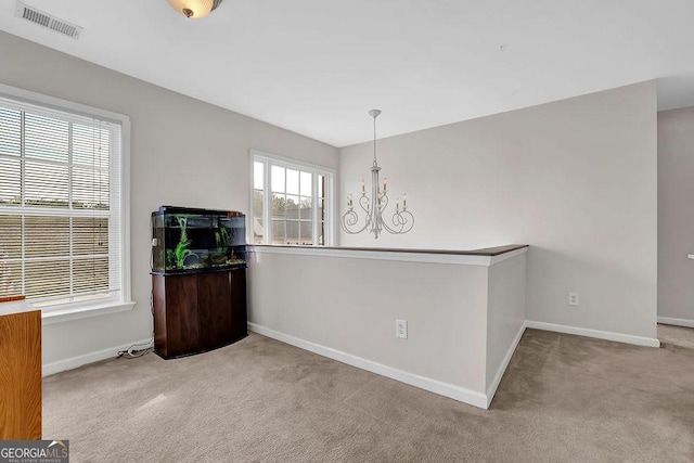 unfurnished dining area featuring light colored carpet and an inviting chandelier