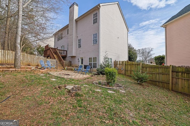 back of house with a wooden deck, a yard, and a patio