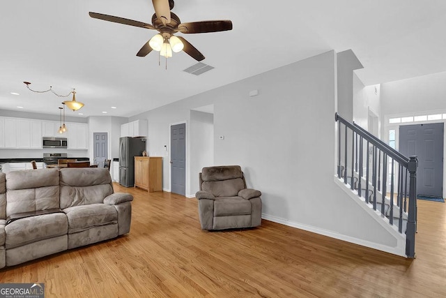 living room with ceiling fan and light hardwood / wood-style flooring