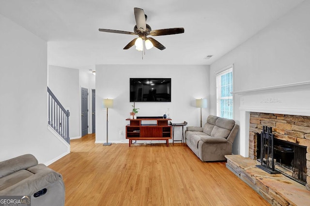 living room with a fireplace, light hardwood / wood-style floors, and ceiling fan