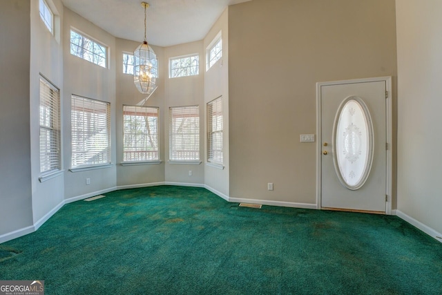 entrance foyer featuring dark carpet, a healthy amount of sunlight, and a high ceiling