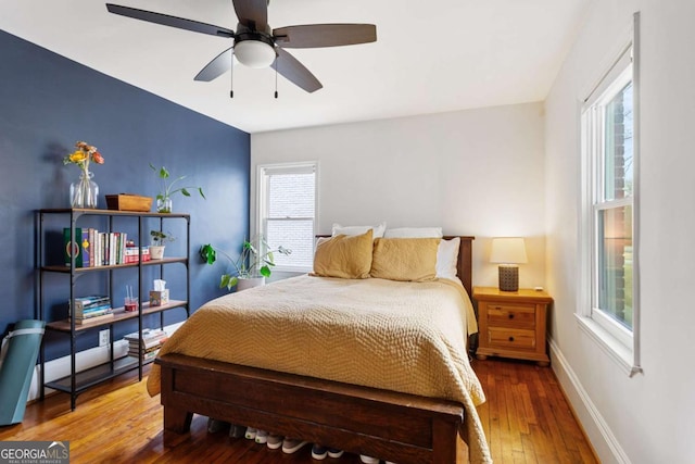 bedroom with multiple windows, hardwood / wood-style floors, and ceiling fan