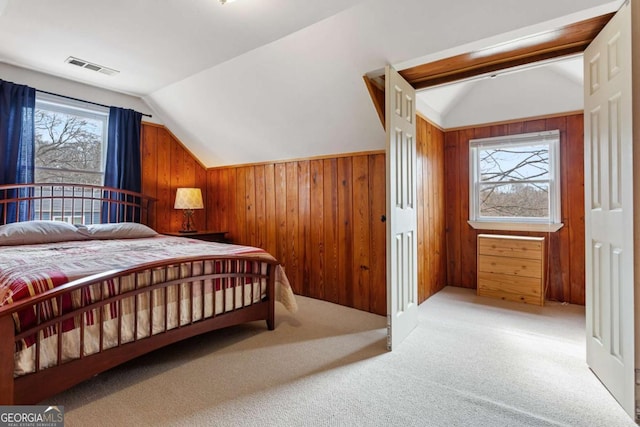 bedroom with light carpet, vaulted ceiling, and wood walls