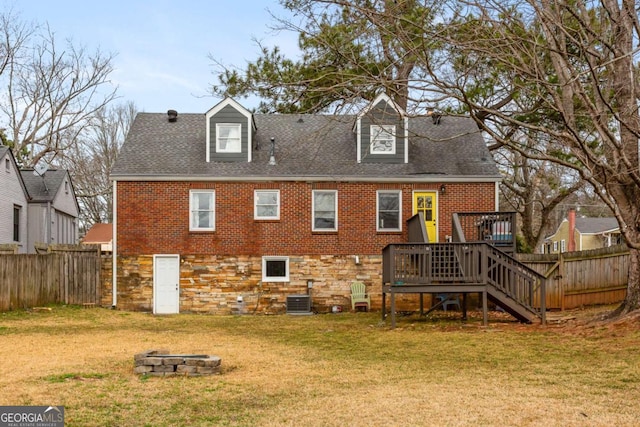 back of house featuring cooling unit, a lawn, a deck, and an outdoor fire pit