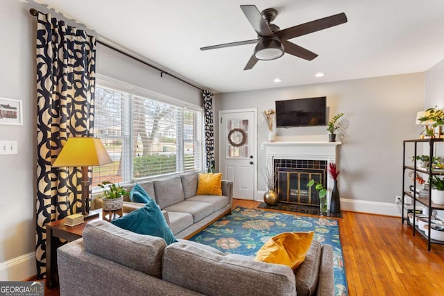 living room with ceiling fan, wood-type flooring, and a fireplace