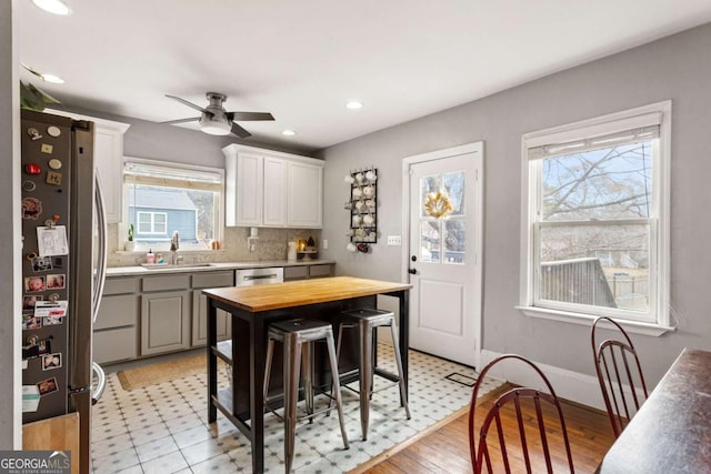 kitchen with sink, appliances with stainless steel finishes, white cabinets, a kitchen bar, and wood counters