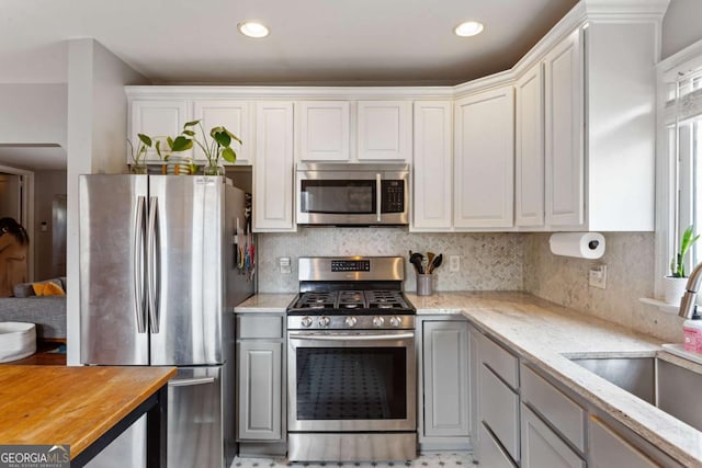 kitchen with white cabinetry, butcher block countertops, and appliances with stainless steel finishes