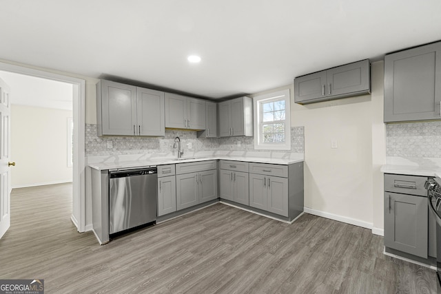 kitchen with tasteful backsplash, stainless steel dishwasher, gray cabinets, and hardwood / wood-style floors