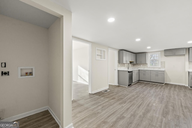 kitchen featuring sink, gray cabinetry, tasteful backsplash, dishwasher, and light hardwood / wood-style floors