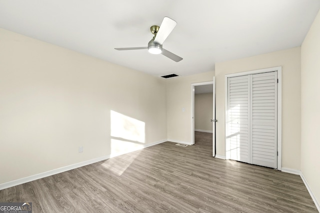 unfurnished bedroom featuring ceiling fan, dark hardwood / wood-style flooring, and a closet