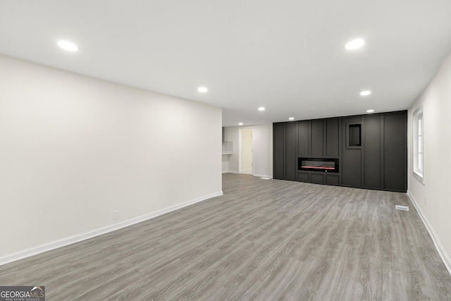 unfurnished living room featuring a large fireplace and light hardwood / wood-style floors