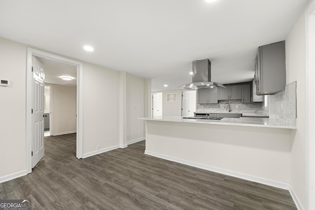 kitchen with sink, gray cabinetry, island range hood, dark hardwood / wood-style flooring, and kitchen peninsula