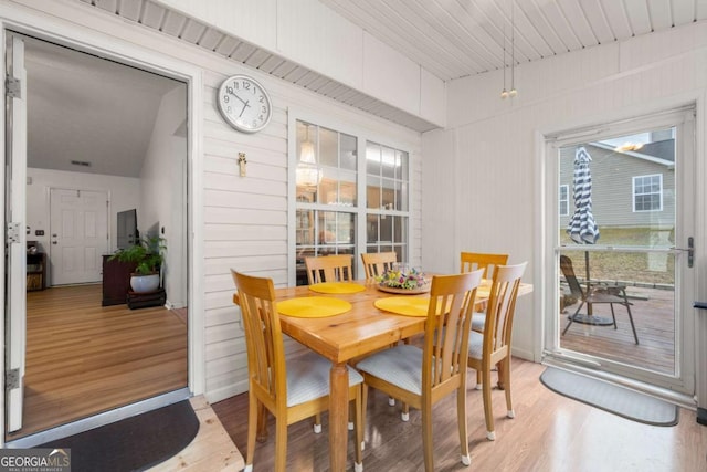 dining area with wood-type flooring and wooden walls