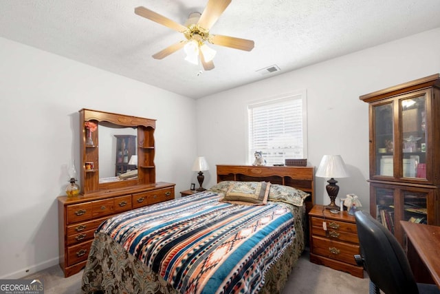 bedroom with ceiling fan, light colored carpet, and a textured ceiling