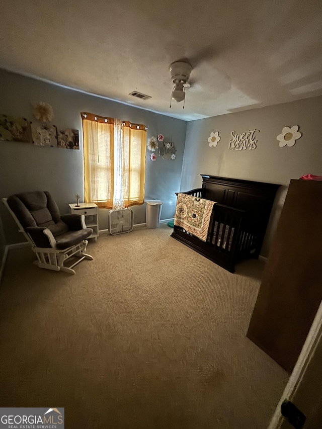 carpeted bedroom featuring a nursery area and ceiling fan