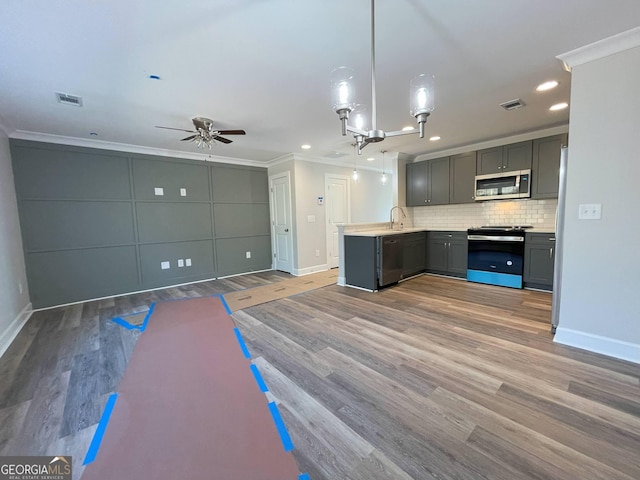 kitchen featuring crown molding, appliances with stainless steel finishes, pendant lighting, and kitchen peninsula