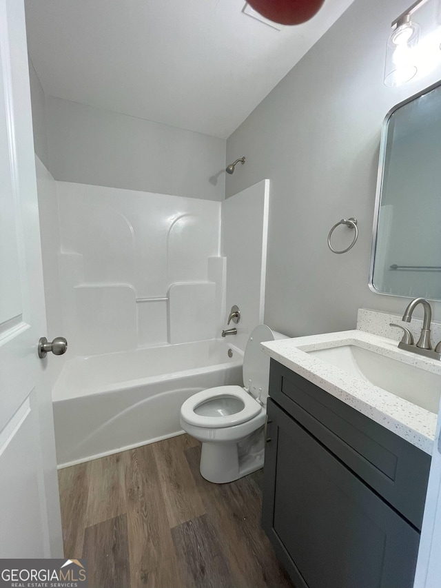 full bathroom featuring vanity, hardwood / wood-style flooring, bathtub / shower combination, and toilet