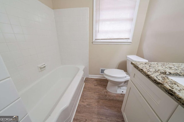 full bathroom with vanity, tiled shower / bath, wood-type flooring, and toilet