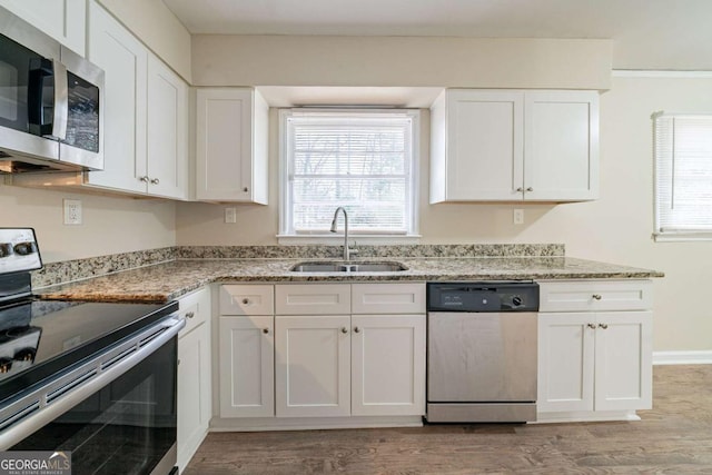 kitchen with appliances with stainless steel finishes, light stone countertops, sink, and white cabinets