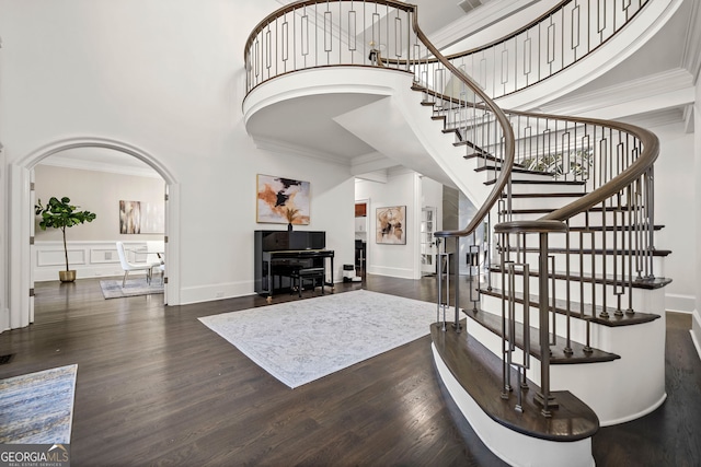 foyer entrance with a high ceiling, ornamental molding, and dark wood-type flooring