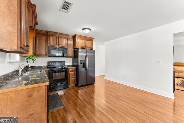 kitchen featuring sink, dark wood-type flooring, and black appliances