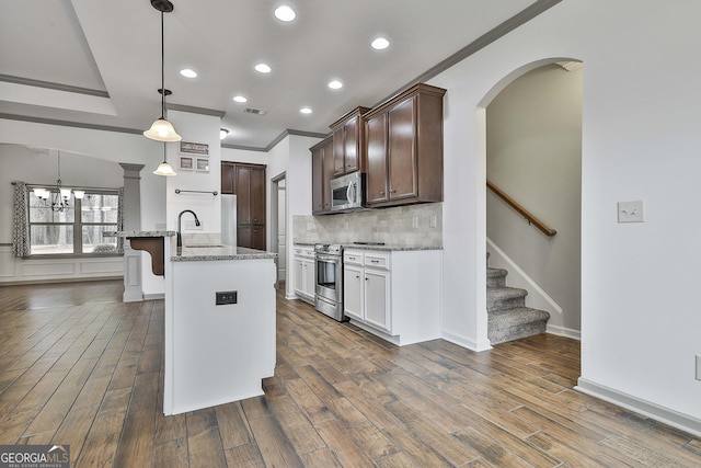 kitchen with decorative backsplash, light stone counters, appliances with stainless steel finishes, dark wood-type flooring, and a sink