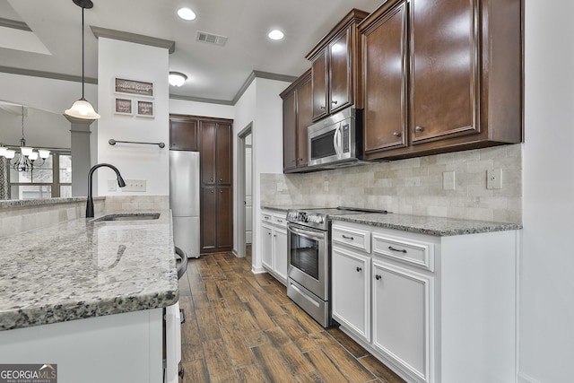 kitchen featuring dark brown cabinetry, decorative backsplash, dark wood-type flooring, stainless steel appliances, and a sink