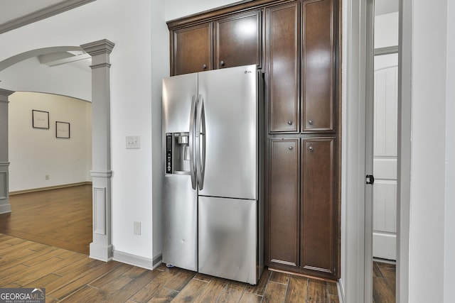 kitchen with ornate columns, dark wood-style floors, arched walkways, and stainless steel refrigerator with ice dispenser