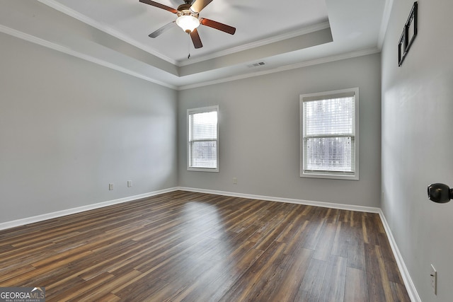 spare room featuring a tray ceiling, dark wood-style flooring, visible vents, and baseboards