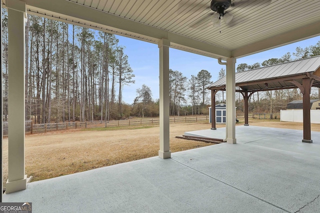 view of patio with a storage shed, ceiling fan, a fenced backyard, and an outbuilding