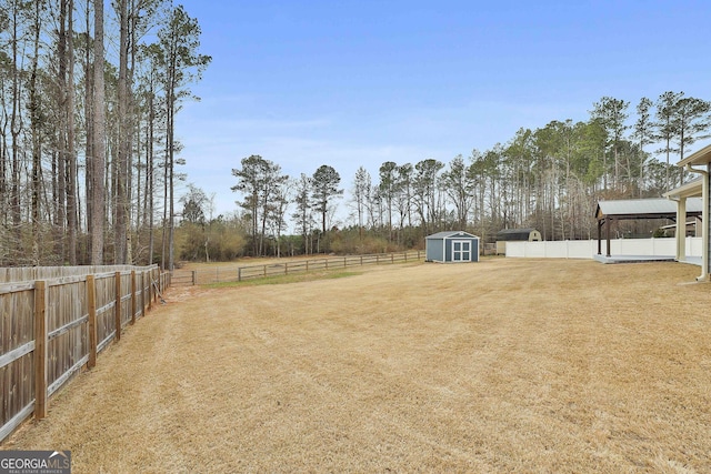 view of yard with a storage shed, a fenced backyard, and an outdoor structure