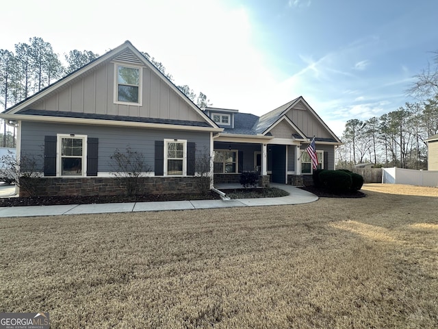 craftsman-style home featuring stone siding, a front lawn, and board and batten siding