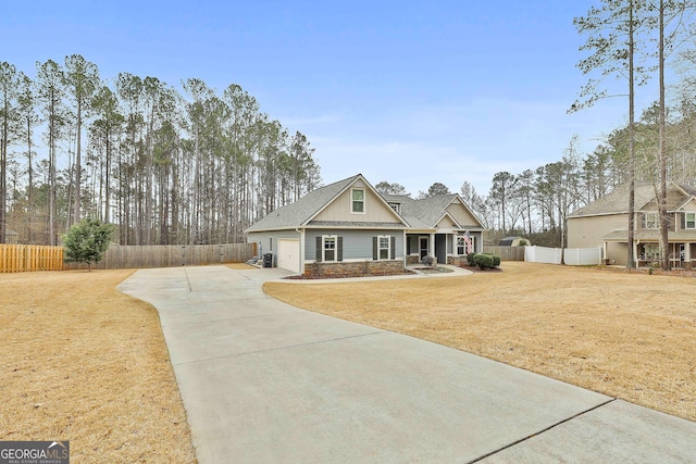 craftsman house with an attached garage, fence, driveway, stone siding, and board and batten siding