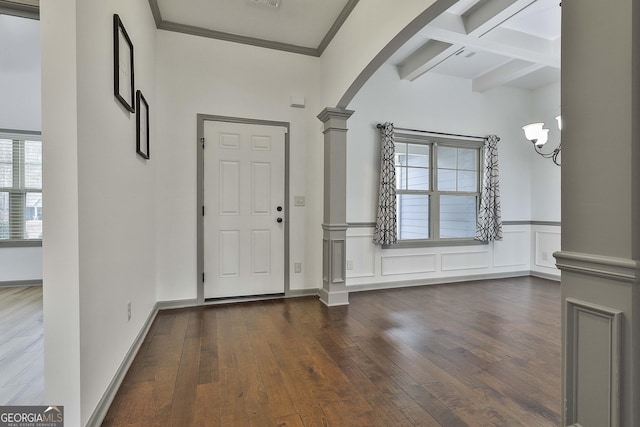 entrance foyer featuring arched walkways, decorative columns, beamed ceiling, and hardwood / wood-style floors