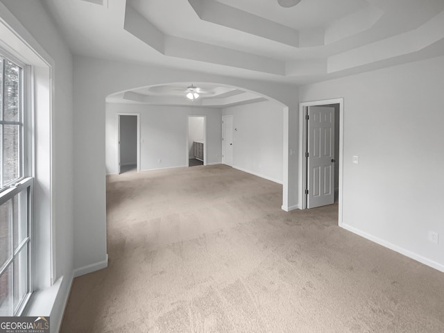 carpeted spare room featuring a tray ceiling and ceiling fan