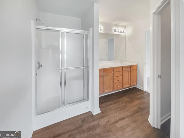 bathroom featuring wood-type flooring, an enclosed shower, and vanity