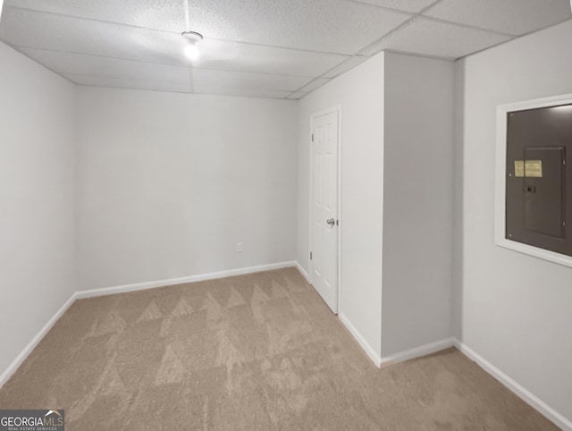 spare room with light carpet, electric panel, and a drop ceiling