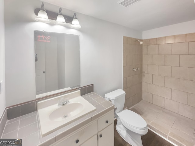 bathroom featuring vanity, a tile shower, and toilet